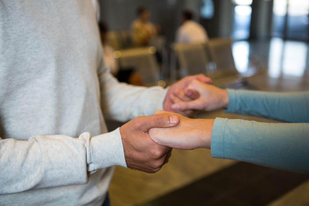couple holding hands waiting area airport terminal (1)